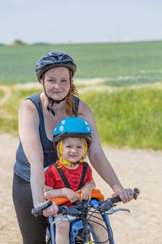 Mother is posing with her little son on the bicycle. All potential trademarks are removed.