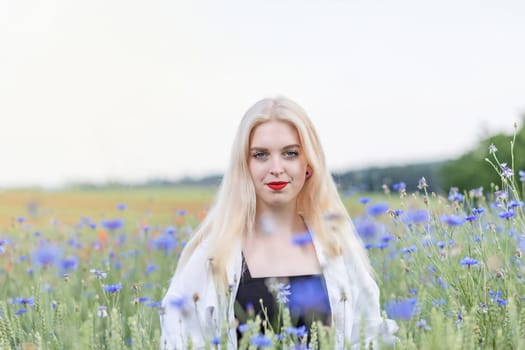 Front view portrait of attractive blonde woman in cornflower meadow. Horizontally.