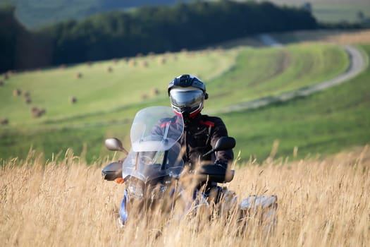 Motorcycle driver riding on countryside hills. Travel and sport, speed and freedom concept