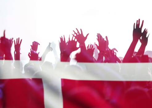 Football fans supporting Denmark - crowd celebrating in stadium with raised hands against Denmark flag