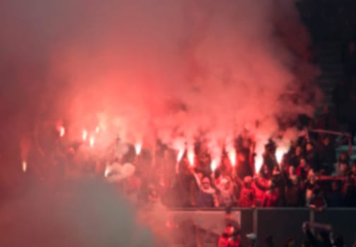 Soccer fans supporting - crowd celebrating in stadium with raised hands against flag