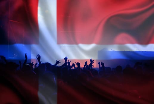 Football fans supporting Denmark - crowd celebrating in stadium with raised hands against Denmark flag