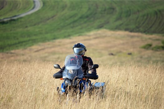 Motorcycle driver riding on countryside hills. Travel and sport, speed and freedom concept