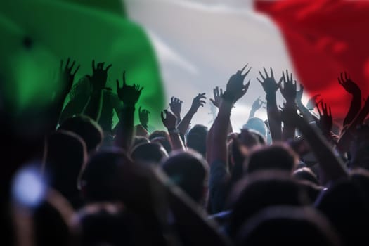 Football fans supporting Italy - crowd celebrating in stadium with raised hands against Italy flag