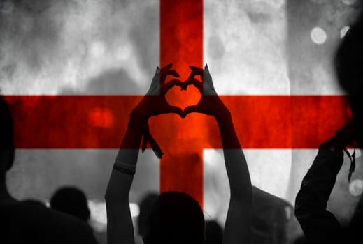 Football fans supporting England - crowd celebrating in stadium with raised hands against England flag