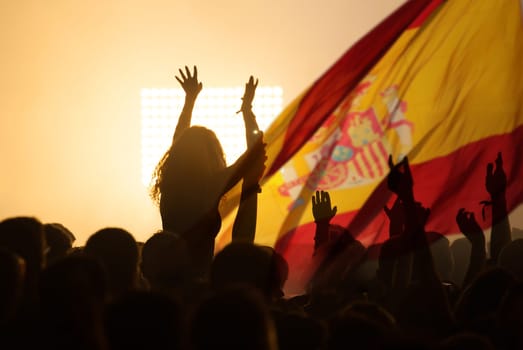 Football fans supporting Spain - crowd celebrating in stadium with raised hands against Spain flag