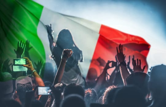 Football fans supporting Italy - crowd celebrating in stadium with raised hands against Italy flag