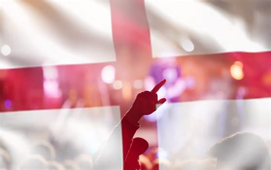 Football fans supporting England - crowd celebrating in stadium with raised hands against England flag