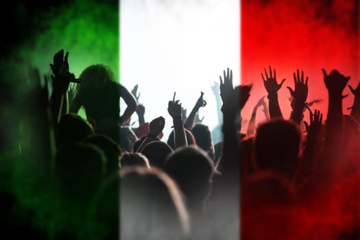 Football fans supporting Italy - crowd celebrating in stadium with raised hands against Italy flag