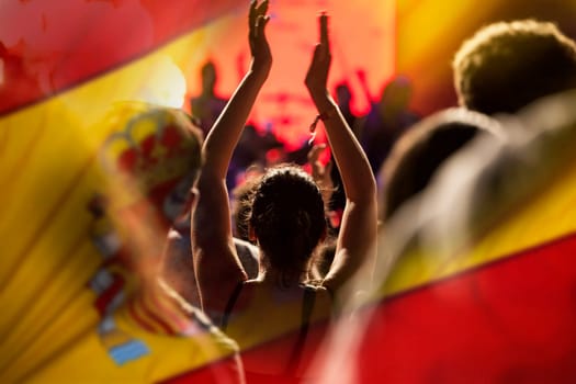 Football fans supporting Spain - crowd celebrating in stadium with raised hands against Spain flag