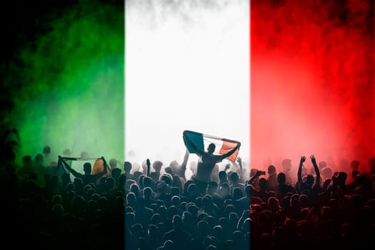 Soccer fans supporting Italy - crowd celebrating in stadium with raised hands against italian flag