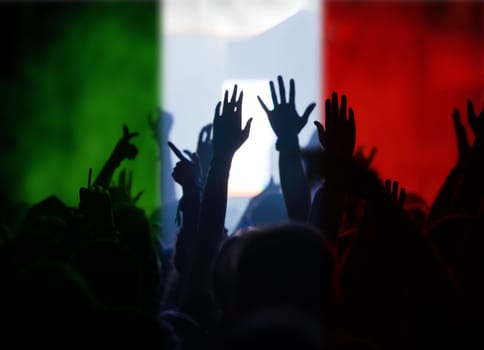Football fans supporting Italy - crowd celebrating in stadium with raised hands against Italy flag