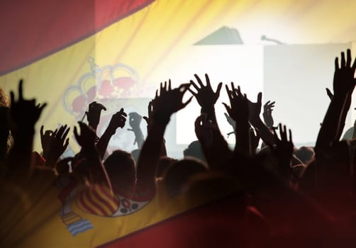 Football fans supporting Spain - crowd celebrating in stadium with raised hands against Spain flag