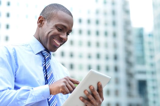Happy businessman checking mails in tablet