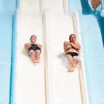 People having fun, sliding at water park.