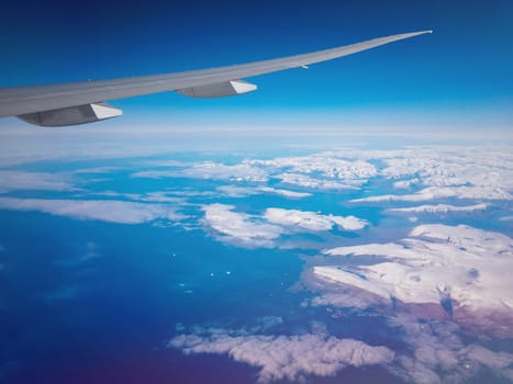 View from plane above Greenland on mountains of ice and sea