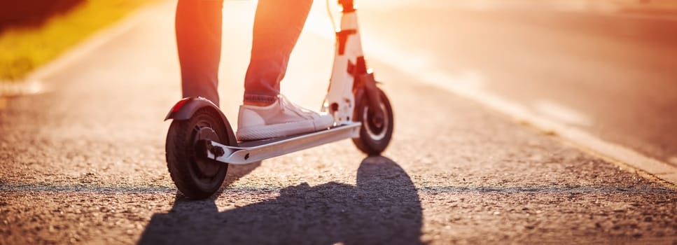 Woman riding on scooter on asphalt in summer. Urban eco transportation