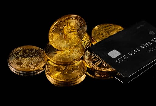 Leader in cryptocurrency BTC and bitcoin rewards card against black surface. Golden coin with bitcoin logo and credit card . Decentralized digital currency. Crypto payment. Electronic money or e-cash
