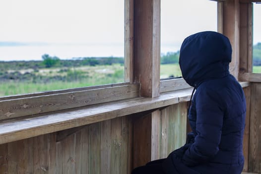 Hooded woman observing Flamingos at Fuente de Piedra lagoon, Malaga, Spain