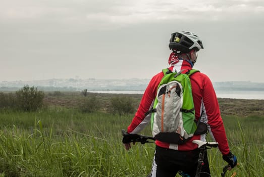 Elder MTB biker observing Flamingos at Fuente de Piedra lagoon, Malaga, Spain