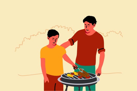 Fatherhood, childhood, holiday, education concept. Young man dad teaching child kid son how to grill standing together in backyard. Family gathering and spending time on summer vacation or fathers day