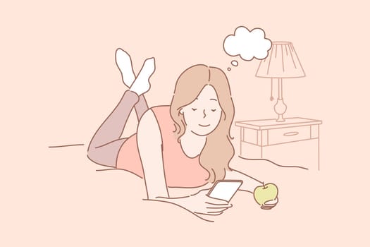 Online communication, social media or network concept. Young woman or girl laying on bed at home eating apple and chatting online using smartphone. Watching videos. Social media, network communication