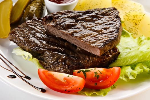 Grilled steaks, French fries and vegetables
