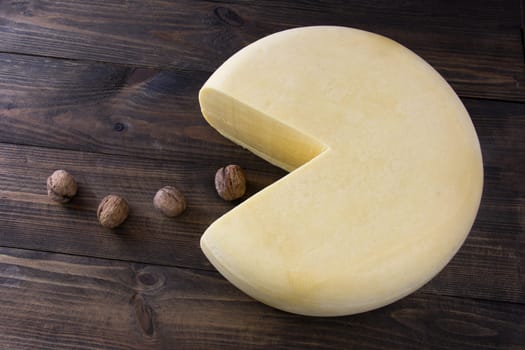 Round cheese eating walnuts on the table