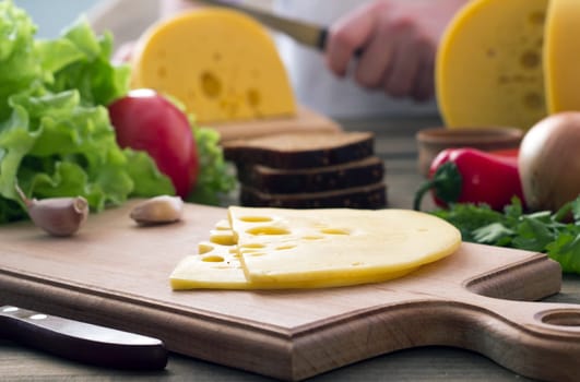 Slice of cheese , vegetables, herbs and bread on a cutting board