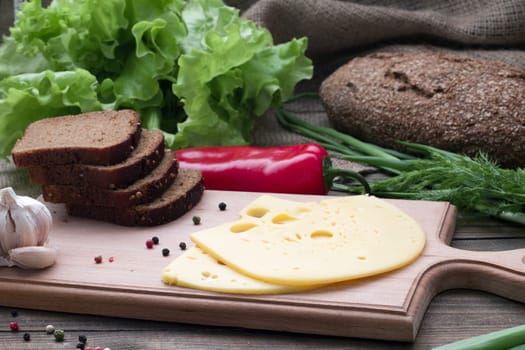 black bread , cheese and fresh herbs on the table