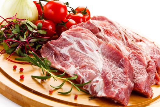 Raw pork chops on cutting board and vegetable