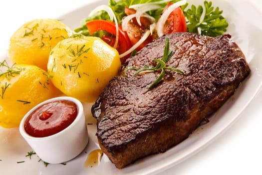 Grilled steaks, boiled potatoes and vegetable salad on white bac