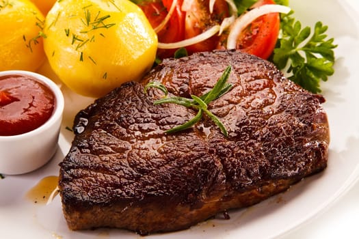 Grilled steaks, boiled potatoes and vegetable salad on white bac
