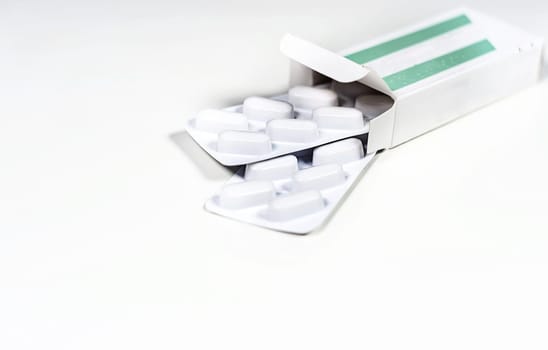 White blister with pills in a green and white box isolated on a white background. Chemistry and medicine. Healthcare and cure concept.