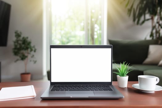 Work from home, workspace, desktop, remote work concept, gray laptop computer with empty white screen mock up on brown wooden table with white cup of coffee, note pad, flowerpot, blurred background