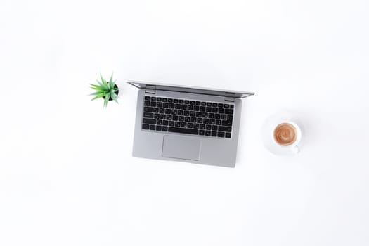 Top view above on gray thin isolated laptop notebook, white cup of espresso coffee, green flowerpot with houseplant on the white background. High quality photo