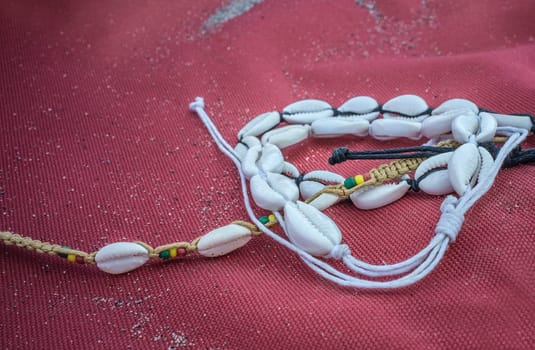 Shell ankle bracelet over red sailcloth fabric. Symbol of summertime