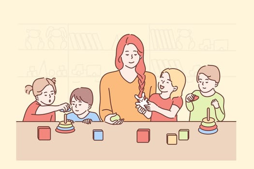 Education, teaching, game, study concept. Young smiling woman teacher cartoon character playing cubes with boys girls children kids preschoolers in kindergarten. Back to school studying process.