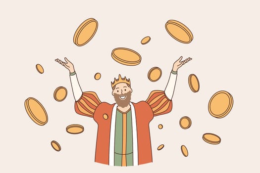 King of coins wealth concept. Young smiling man king in crown cartoon character standing with hands raised up in flying around golden coins feeling happy and confident