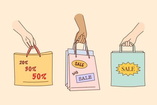 Big sale, shopping, discount in shops concept. People hands holding colorful shopping or gift bags with sale percents and discounts signs and symbols over yellow background illustration