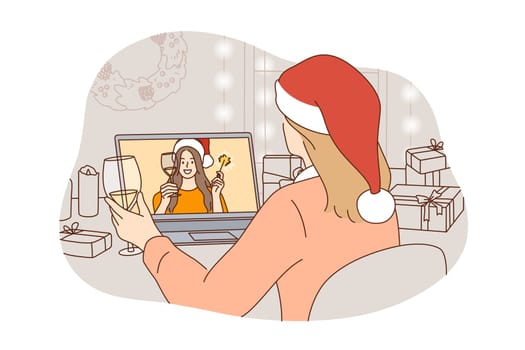 Christmas, New Year online celebrating during lockdown concept. Young woman in festive hat and glass of champagne celebrating winter holidays online on laptop with friend during quarantine pandemic