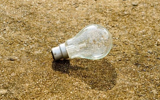 One transparent fluorescent Light bulb in the sunlight with shadow on the floor. Renewable energy technology ecology background.