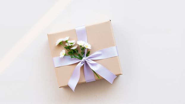 The gift comes in minimalist packaging, decorated with a neutral, calm purple ribbon and flowers symbolizing the arrival of spring. High quality photo