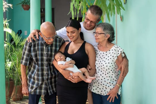 Photo of a group of people. A baby in the arms of a young woman, a man and an elderly couple