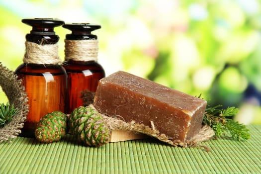 Hand-made soap and bottles of fir tree oil on bamboo mat