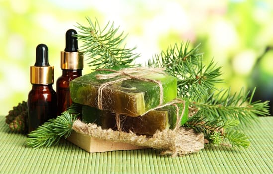 Hand-made soap and bottles of fir tree oil on bamboo mat