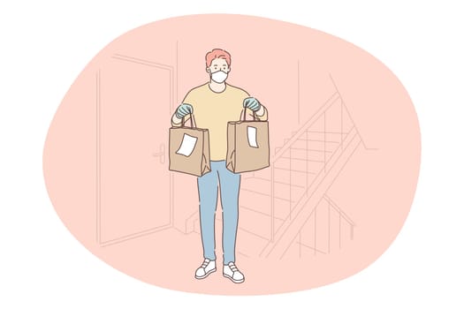 Contactless delivery, courier, online order concept. Young man courier deliveryman in protective medical mask gloves delivering food in paper bags to customer home. Parcel, logistics during pandemic