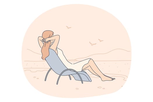 Summer, vacation, relax concept. Woman sitting on beach chair and looking at calm sea and seagulls enjoying seaside recreation watching seascape. Holiday rest and summertime sunbathing on sand