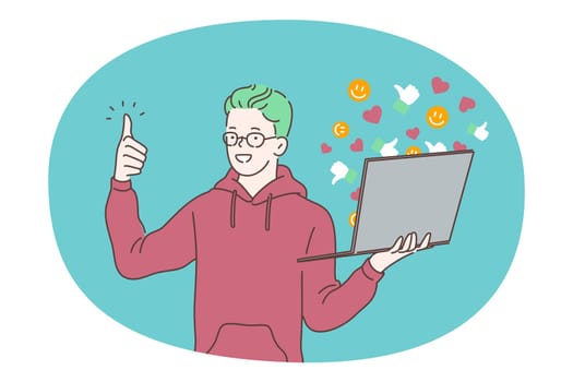 Online communication, e-learning, laptop concept. Young smiling boy standing with laptop and showing thumbs up sign with finger. Communicating online with friends, studying, watching distant courses