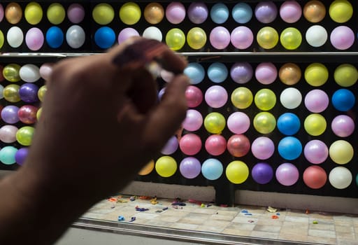 A hand pointing at fairground balloon dart game. Motion blurry hand